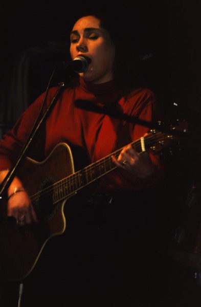 The image shows Lois standing with her guitar