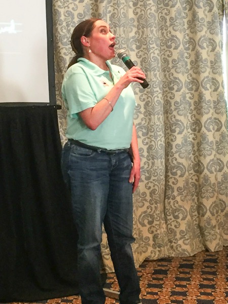 the image shows Lois speaking into a microphone