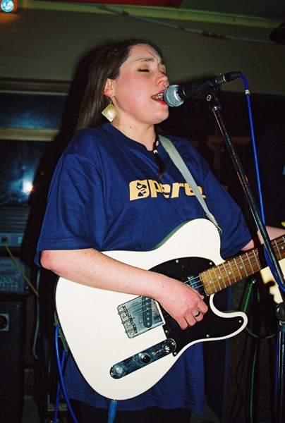 the image shows Lois playing guitar and singing into a microphone