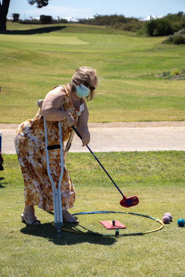 Lady with a crutch plays golf